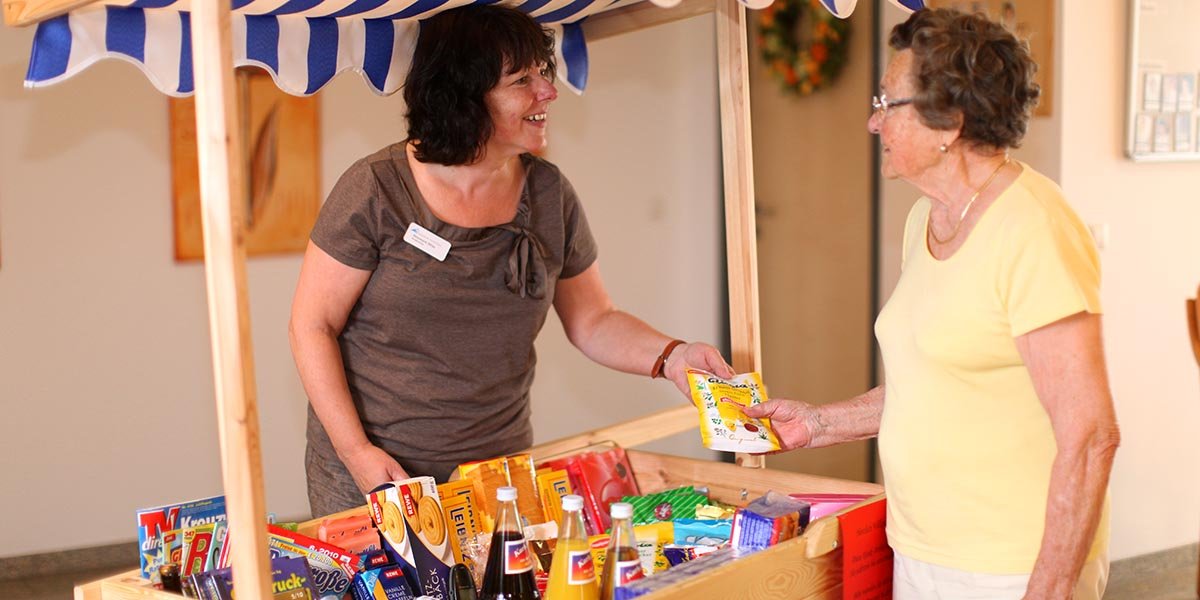 Eine Mitarbeiterin gibt älteren Dame Bonbons