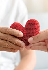 Zwei Hände halten gestricktes Herz